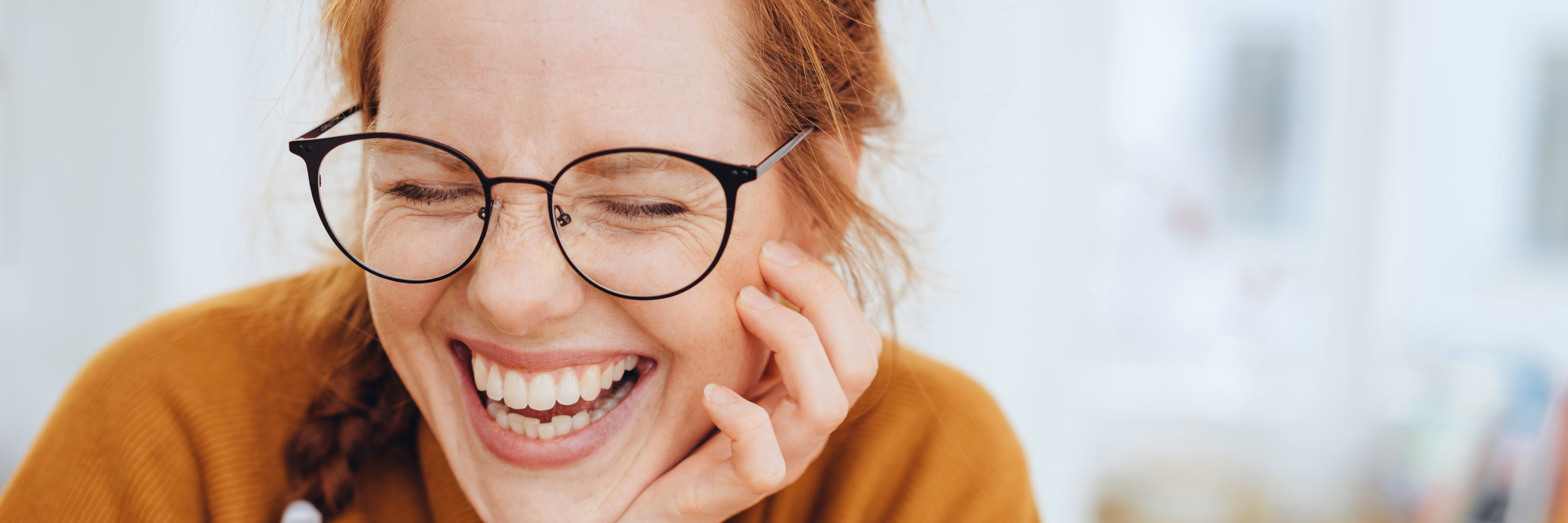 Lachende Frau mit Brille und roten Haaren