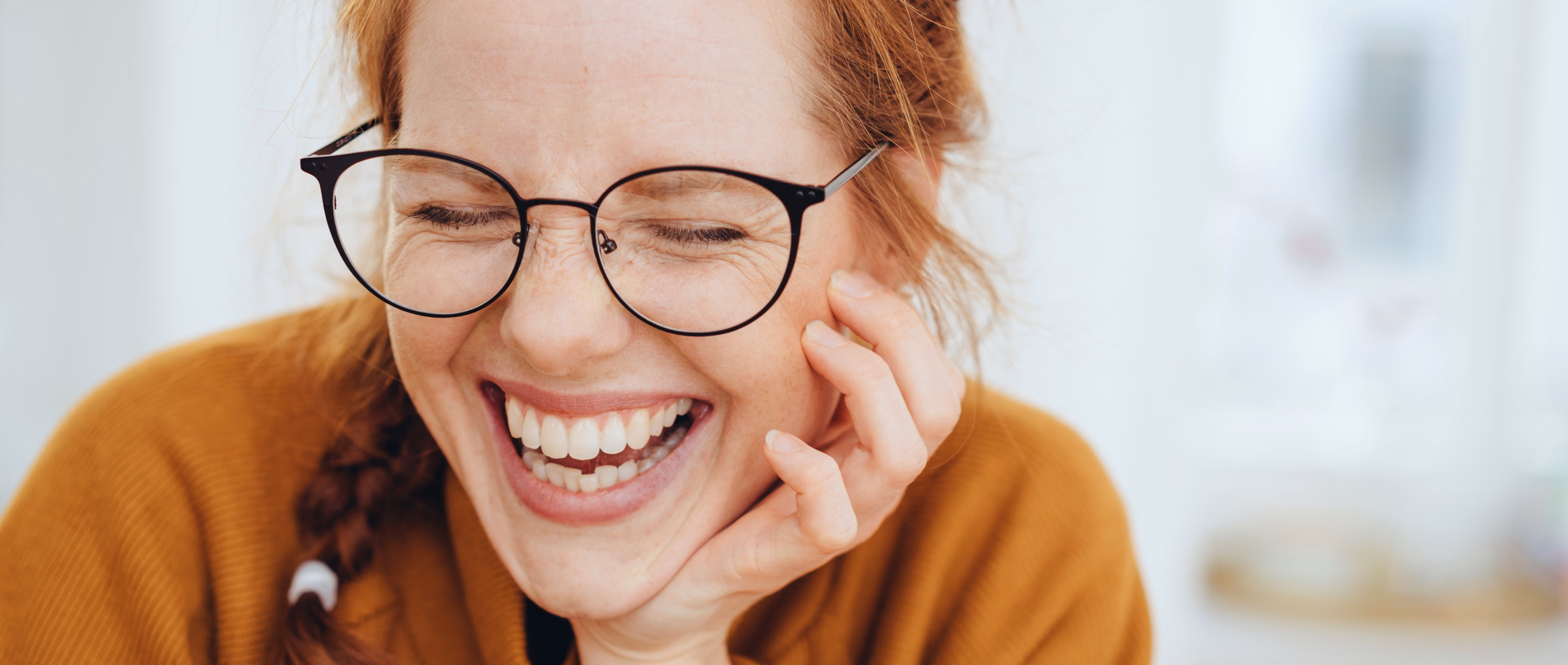 Lachende Frau mit Brille und roten Haaren